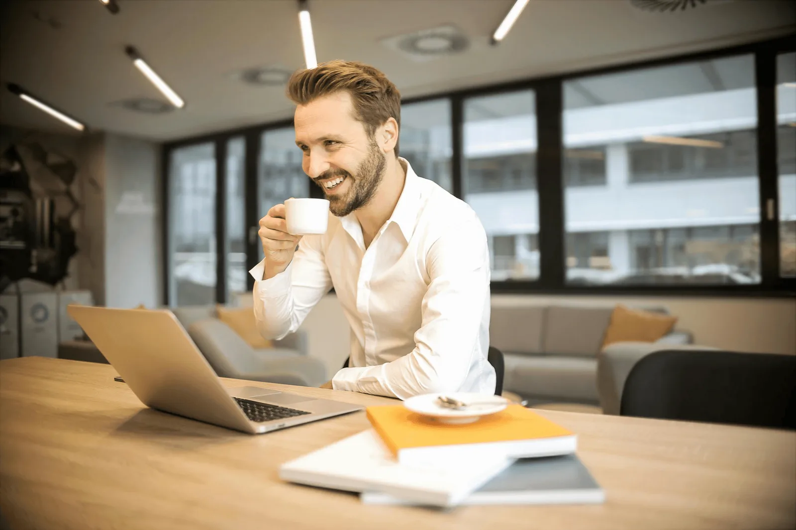 Pemilik bisnis tersenyum sambil memantau laporan di laptop
